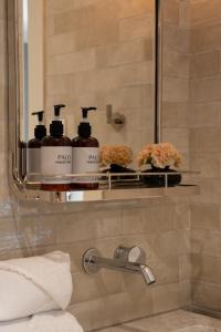 a bathroom with three bottles of soap and a mirror at Manoir Émery in Montreal