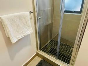 a shower with a glass door and a towel at Otgreen suites in Gaborone