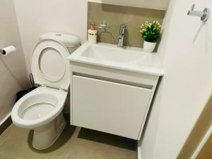 a white bathroom with a toilet and a sink at Otgreen suites in Gaborone