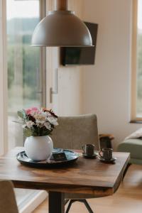 a table with a vase of flowers and two cups at Natururlaub by Klotz TINY HAUS c in Überlingen