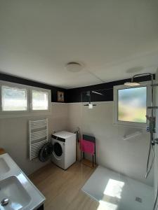a bathroom with a sink and a washing machine at Le clos de Tallann in Guénin