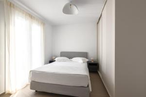 a white bedroom with a white bed and windows at Estia Villas Naxos in Naxos Chora