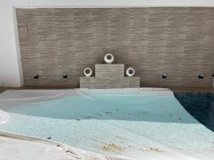 a swimming pool in a room with a brick wall at Résidence MuHamin in Ngaparou