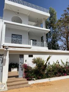 a white building with a balcony and flowers at Résidence MuHamin in Ngaparou