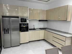 a kitchen with stainless steel appliances and wooden cabinets at Résidence MuHamin in Ngaparou