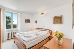 a white bedroom with a bed and a window at Casa Naima: Family House | Terrace & Peaceful Location - Happy Rentals in Breno