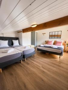 two beds in a large room with wooden floors at Chalet Hotel Alpaka in Châtel