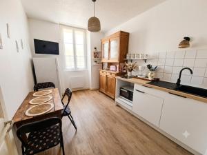 a kitchen with a wooden table and a table and chairs at Le Chapitre in Châteaumeillant
