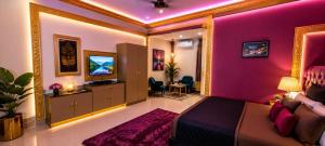 a bedroom with pink walls and a bed and a tv at P'almshore Ecr' Resort in Mahabalipuram