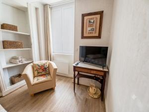 a living room with a chair and a table and a television at Le Chapitre in Châteaumeillant