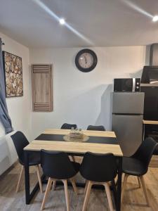 a dining room table with chairs and a clock on the wall at chic apartment and zen in Chauray +5 photos
