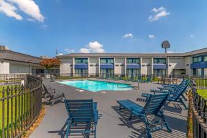 a pool with blue chairs in front of a building at Red Lion Inn & Suites Kansas City in Kansas City