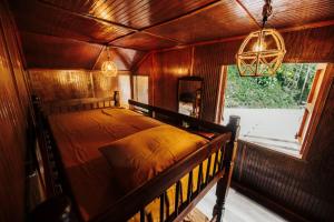 a bed in a wooden room with a window at Naranjito River Retreat Events & Groups Sleeps 13 in Naranjito