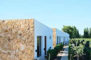 a row of white buildings with a stone wall at Rincon del Malbec 3 in Ciudad Lujan de Cuyo