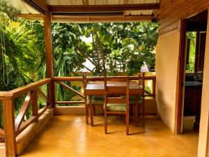 a wooden table and chairs on a balcony with trees at Villas Don Che, 2 villas in Jarabacoa
