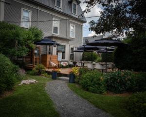 a garden with a bench and umbrellas in front of a house at Le Pleasant Hôtel in Sutton