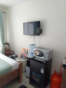 a bedroom with a bed and a tv on a table at Le Kirstel Suites in Kiambu