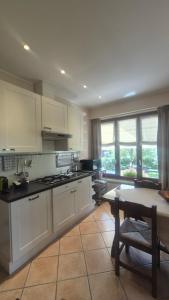a kitchen with white cabinets and a table and a dining room at I Quattro Ulivi - Iseo Lake in Marone