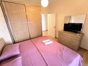 a bedroom with a purple bed and a flat screen tv at Astir Apartments in Tirana