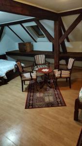 a living room with a table and chairs and a rug at Vila Olga in Sombor