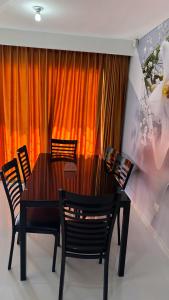 a dining room table with chairs and an orange curtain at Palmera africana 1 in Los Paredones +5 photos
