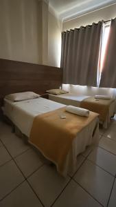 two beds sitting in a room with a window at Pé da Serra Hotel in Resende