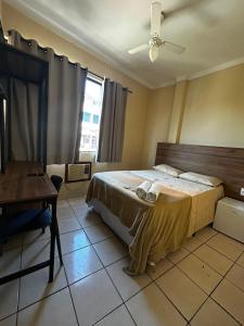 a bedroom with a bed and a desk and a window at Pé da Serra Hotel in Resende