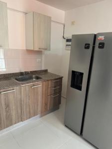 a kitchen with a stainless steel refrigerator and wooden cabinets at Palmera africana 1 in Los Paredones