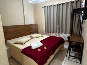 a bedroom with a bed and a chair and a table at Pé da Serra Hotel in Resende