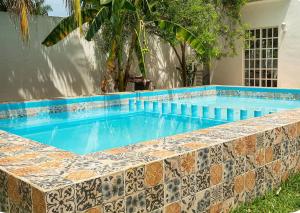 a swimming pool with a tiled wall next to a house at Villas Aura in Mérida
