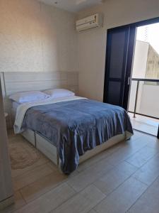 a bedroom with a bed with a blue blanket on it at Pousada Brisa da Mata in Londrina