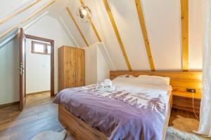 a bedroom with a bed with a purple comforter at Brvnara Mont in Zlatibor