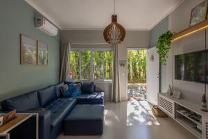 a living room with a blue couch and a large window at Flat completo e charmoso no centro de Juquehy in São Sebastião