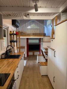 a kitchen with white cabinets and wooden floors at Tiny House Azyl Wolności in Pozezdrze