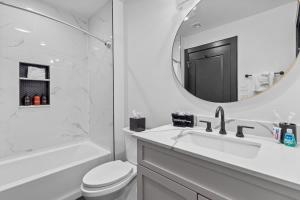a white bathroom with a sink and a mirror at King Bed Prime Location Downtown Hotel Suite in New Orleans