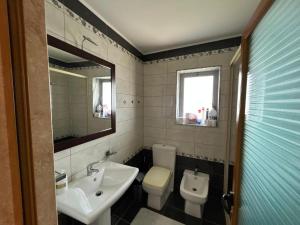 a bathroom with a sink and a toilet and a mirror at Apartment golem in Durrës