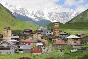 a town on a hill with mountains in the background at Hotel - Old Ushguli in Ushguli
