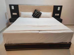 a large bed with white sheets and pillows on it at Hostel Arabbian nights in Khajurāho