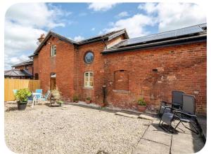 a red brick building with a patio in front of it at The Hurst Stable Sleeps 4 with Hot Tub & Parking in Stafford
