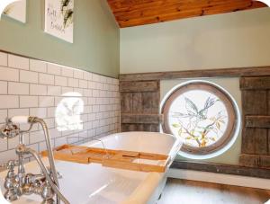 a bathroom with a tub and a round window at The Hurst Stable Sleeps 4 with Hot Tub & Parking in Stafford +12 photos