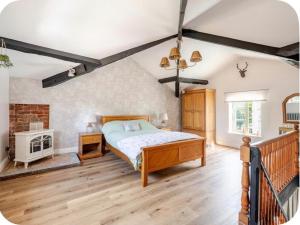 a bedroom with a bed and a wooden floor at The Hurst Stable Sleeps 4 with Hot Tub & Parking in Stafford