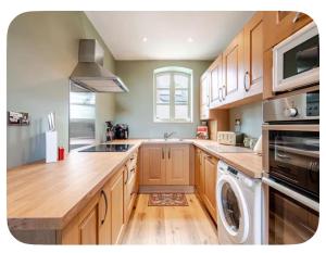 a kitchen with wooden cabinets and a washer and dryer at The Hurst Stable Sleeps 4 with Hot Tub & Parking in Stafford