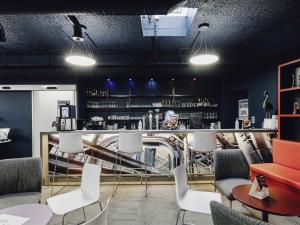 a restaurant with a bar with white chairs and tables at ibis Styles Nancy Laxou in Nancy