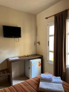 a room with a bed and a desk and a refrigerator at Marchetti Hotel Comedor in Miramar
