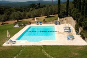 a swimming pool in a field with two lawn chairs at Residenza d'Epoca Il Cassero in Lucignano
