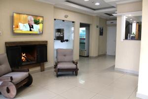 a waiting room with a fireplace and a tv at Hotel Guaíba in Guaíba +19 photos