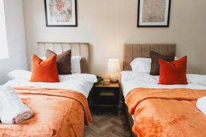 two beds with orange pillows in a room at The High Town Suite in Luton