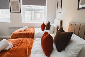 a bedroom with two beds with orange pillows at The High Town Suite in Luton