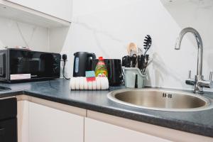 a kitchen counter with a sink and a microwave at The High Town Suite in Luton +3 photos