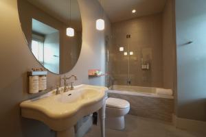 a bathroom with a sink and a toilet and a mirror at Le Pleasant Hôtel in Sutton +64 photos